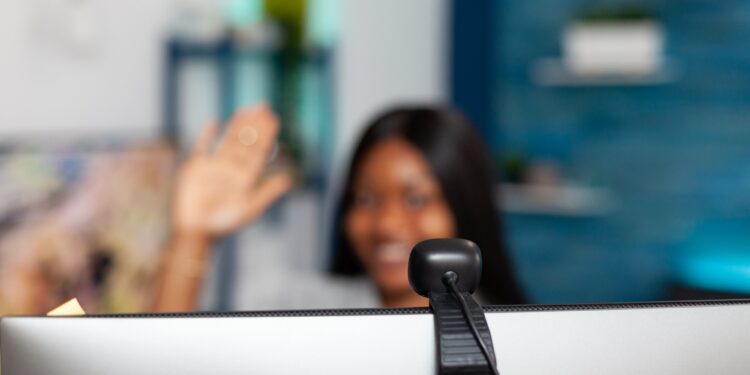 African american student waving teacher discussing university lesson course during online videocall meeting conference working remote from home. Selective focuse on computer webcam
