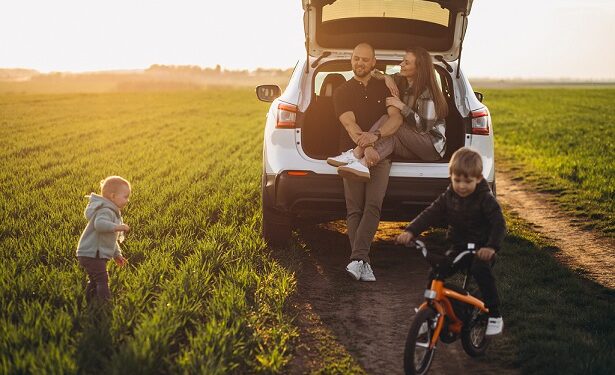 Young family with kids travelling by car, stopped in the field
