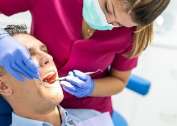 Young Dentist Woman Doing a Check Up to a Patient. Man Going to the Dentist. Man Getting a Checkup at the Dentist Clinic. Healthcare Concept.