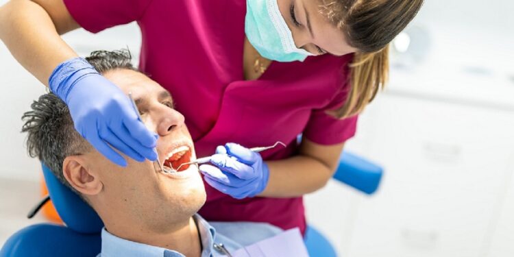 Young Dentist Woman Doing a Check Up to a Patient. Man Going to the Dentist. Man Getting a Checkup at the Dentist Clinic. Healthcare Concept.