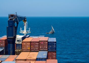 African wooden sailboat crossing container vessel way at close distance.; Shutterstock ID 1891608787; ordering_party: CMS CMNO; job_project: six-part Belt and Road series (Africa); purchase_order: Craig Moseley