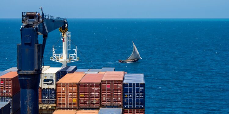 African wooden sailboat crossing container vessel way at close distance.; Shutterstock ID 1891608787; ordering_party: CMS CMNO; job_project: six-part Belt and Road series (Africa); purchase_order: Craig Moseley