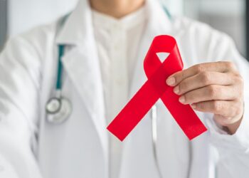 Aids red ribbon in doctor's hand for World aids day and HIV virus awareness concept