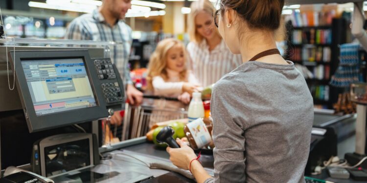 Beautiful family standing at the cash counter buying groceries at the supermarket