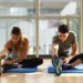 Young woman and man working out indoors. Two people streching their legs on the floor of a gym.