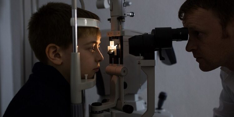 Optician testing a boy's eyes with optometry devices