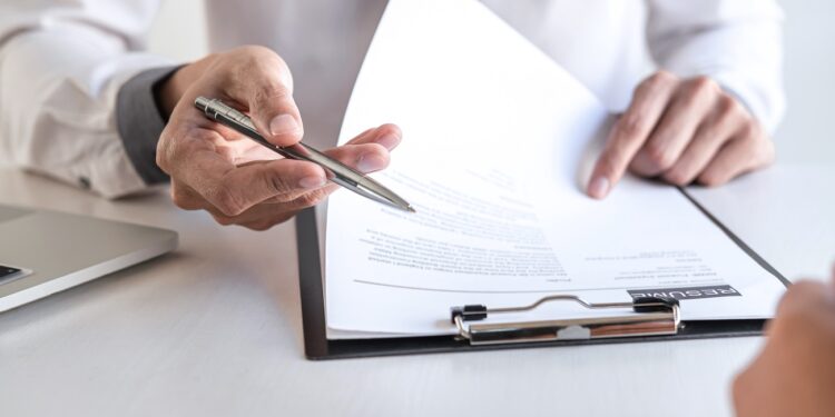 Employer or recruiter holding reading a resume during about colloquy his profile of candidate, employer in suit is conducting a job interview, manager resource employment and recruitment concept.
