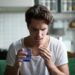 Millennial man taking antibiotic antidepressant painkiller pill medication to relieve pain at home, young guy feeling sick ill suffering from headache, stress or flu, emergency treatment concept