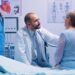Elderly woman doctor appointment in modern private clinic while she sitts on hospital bed and the physician is listening her heart beat. Health care medicine treatment, specialist consultation