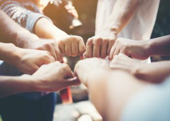 Close up of young people putting their hands together. Team with stack of hands showing unity and teamwork.