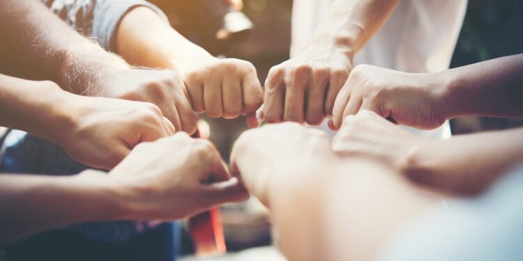 Close up of young people putting their hands together. Team with stack of hands showing unity and teamwork.