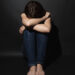 Depressed young woman with head in hands sitting lonely.