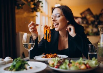 Young woman eating pasta in a cafe