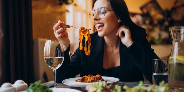 Young woman eating pasta in a cafe