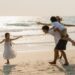 Asian young happy family enjoy vacation on beach in the evening. Dad, mom and kid relax playing together near sea when sunset while travel holiday. Lifestyle travel holiday vacation summer concept.