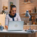 Excited woman feel ecstatic reading great online news on laptop working from home kitchen. Happy employee using modern technology network wireless doing overtime studying writing, searching