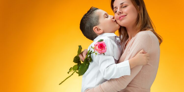Young kid giving red rose to his mom on orange background