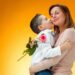 Young kid giving red rose to his mom on orange background