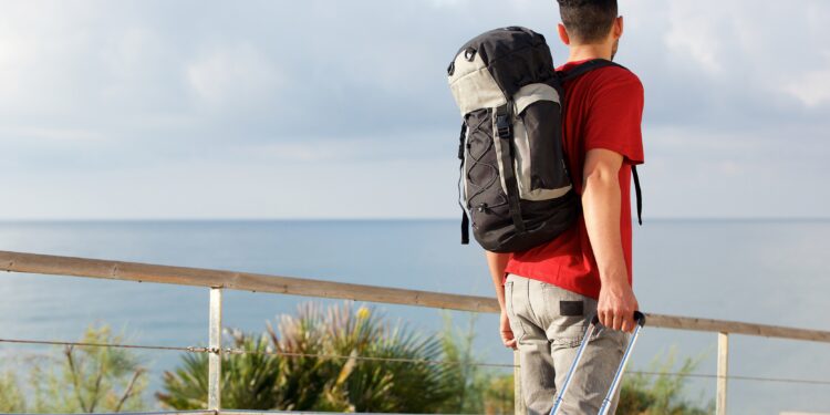 Rear view of man traveling with backpack and suitcase