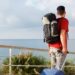 Rear view of man traveling with backpack and suitcase