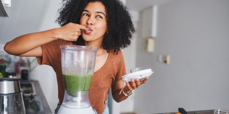 Shot of a young woman making a healthy smoothie at home