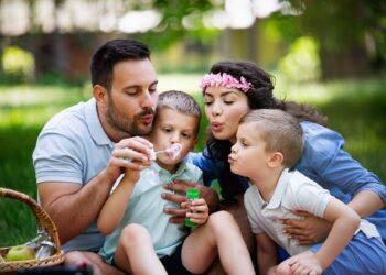 Happy family with children blow soap bubbles outdoor