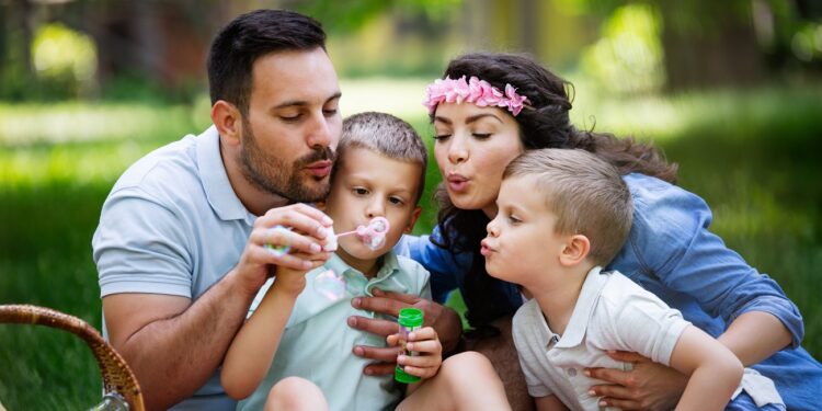 Happy family with children blow soap bubbles outdoor