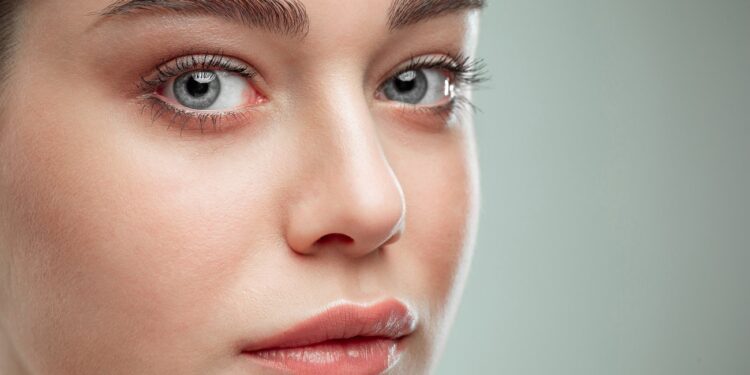 The beautiful female face. The perfect and clean skin of face on gray