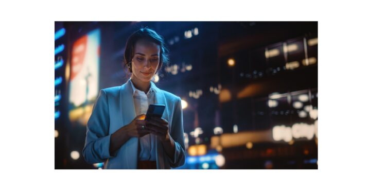 Beautiful Young Woman Using Smartphone Walking Through Night City Street Full of Neon Light. Portrait of Gorgeous Smiling Female Using Mobile Phone.