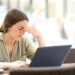 Fatigued woman suffering eyestrain working with a laprop sitting in a coffee shop