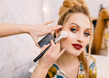 Preparing to party, carnival, celebration of attractive young women in beauty salon. Making makeup, stylish coiffure, professional stylist, cheerful mood, fashionable model