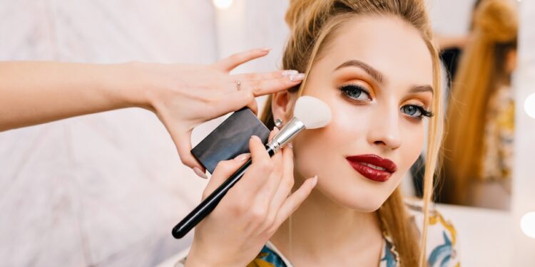 Preparing to party, carnival, celebration of attractive young women in beauty salon. Making makeup, stylish coiffure, professional stylist, cheerful mood, fashionable model
