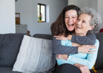 Portrait of happy mid adult woman embracing her senior mother. Mother and daughter at home, family scene. Family relationships concept