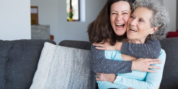Portrait of happy mid adult woman embracing her senior mother. Mother and daughter at home, family scene. Family relationships concept