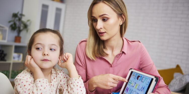 Bored girl and her mother studying with laptop at home