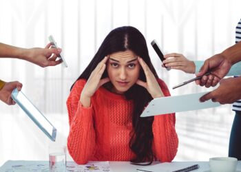 Stresssed woman sitting with hands on forehead in office