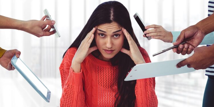 Stresssed woman sitting with hands on forehead in office