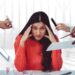 Stresssed woman sitting with hands on forehead in office