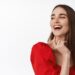 Close up portrait of attractive young woman in red dress, evening make up, laughing and smiling happy, enjoying party, looking aside at logo banner, read promo text, white background.