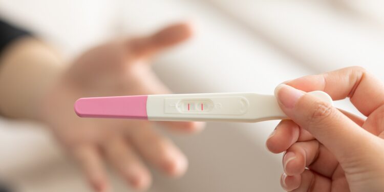 A closeup of a wife giving a positive pregnancy test to the husband with a blurry background