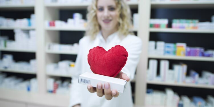 Pharmacist in white uniform holding medicines for cardiovascular disease.