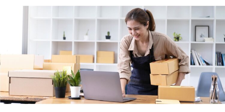 Young smiling beautiful owner asian woman freelancer sme business online shopping working on laptop computer with parcel box at home - SME business online and delivery concept.
