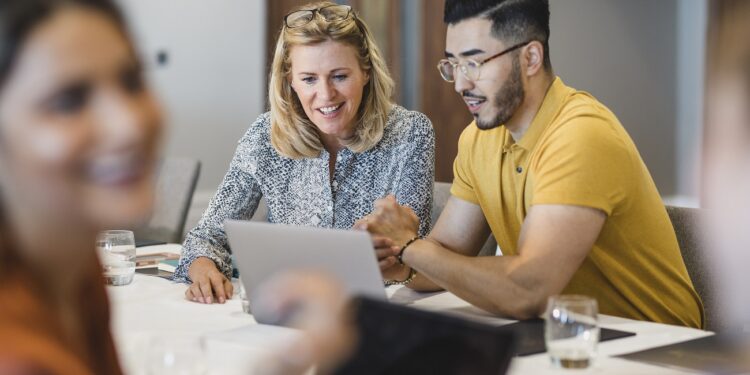 Mature businesswoman smiling with employee, working together, collaboration, teamwork