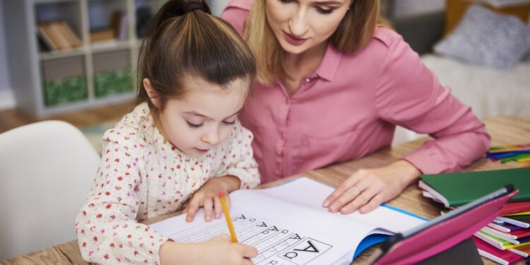Young woman helping girl with homework