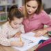 Young woman helping girl with homework