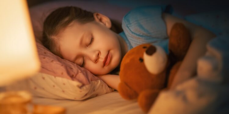 Adorable little child is sleeping in the bed.