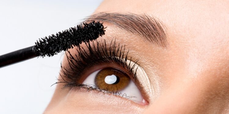 Woman applying mascara on her eyelashes - macro shot