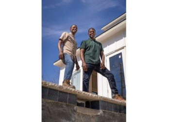 Hosts Chris & Calvin LaMont posing for a photo in front of a swimming pool install in Dallas, Texas, as seen on Buy It or Build It.