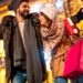 Beautiful young couple in love having fun doing Christmas shopping, walking down decorated city streets carrying shopping bags