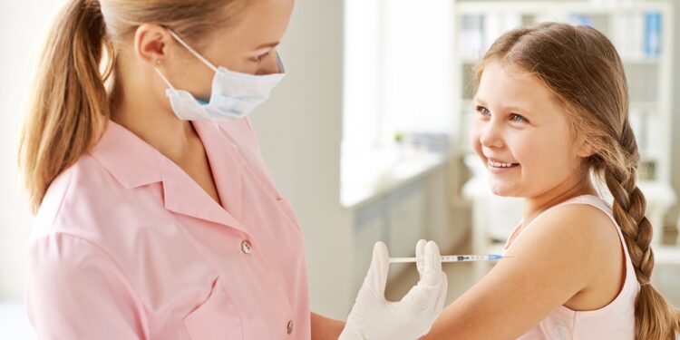 Adorable girl looking at nurse while she making her an injection in clinics